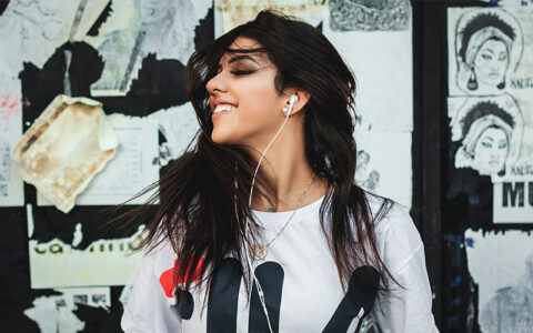 woman with ear pods smiling and dancing while listening to music.