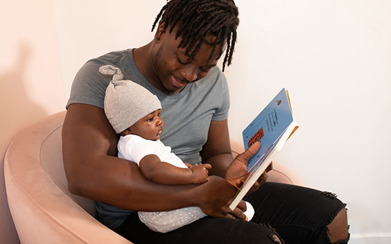 Father reading a board book to his infant child.