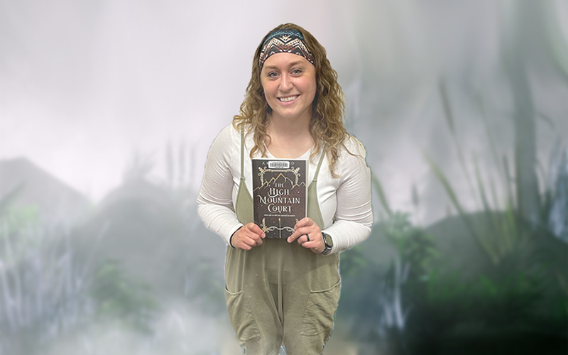 Woman holding a book book against a foggy background.