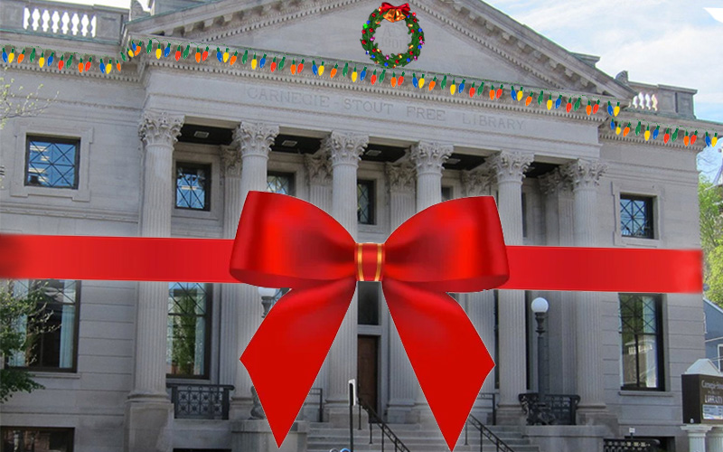 Library building wrapped in a bow and decorated with holiday lights and a wreath.