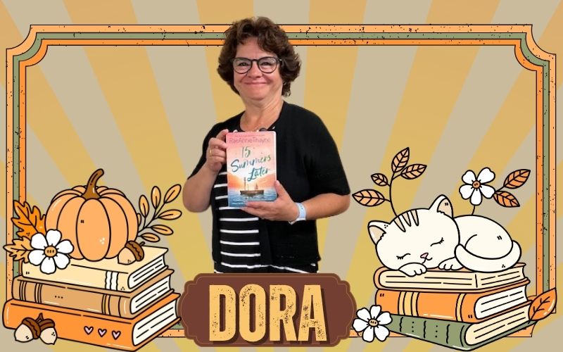 A woman stands holding a book in front of an orange and brown background with orange books, leaves and pumpkins. A cat sleeps on a pile of books.
