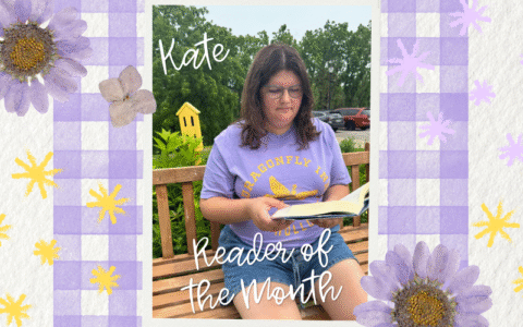 A woman with brown hair and glasses is reading on a bench with plants behind her. The photo is in front of a background with purple gingham pattern and flowers.